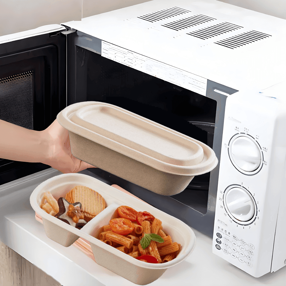 شخص يقوم بوضع حاوية طعام قابلة للتحويل إلى سماد في الميكروويف مع أكواب وأدوات مائدة صديقة للبيئة على المنضدة، مما يوضح العبوات المستدامة الآمنة في الميكروويف من شركة Bioleader.