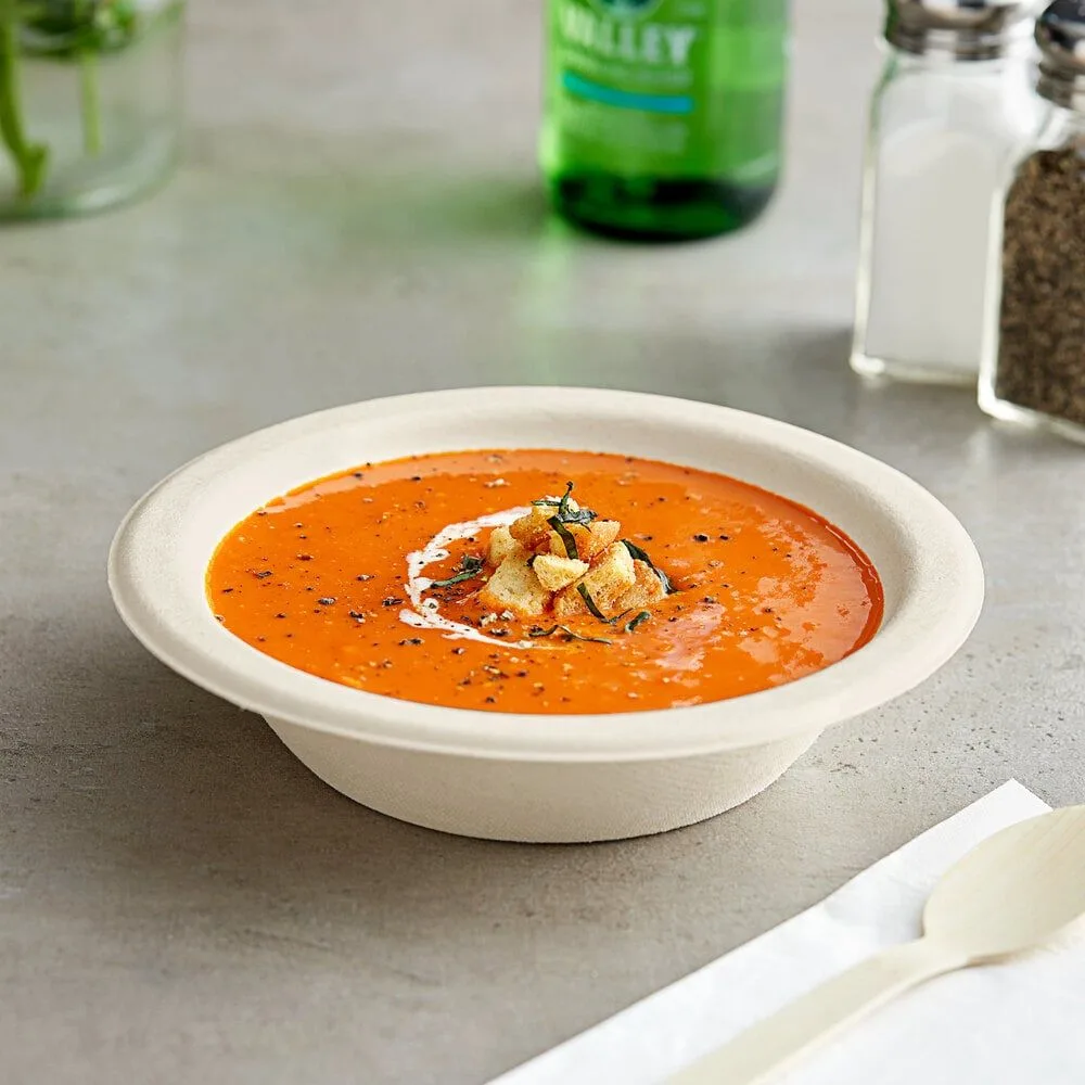 Cuenco hondo de bagazo lleno de sopa de tomate caliente, que presenta una gran resistencia al calor y una estructura robusta para envasar comida caliente para llevar.