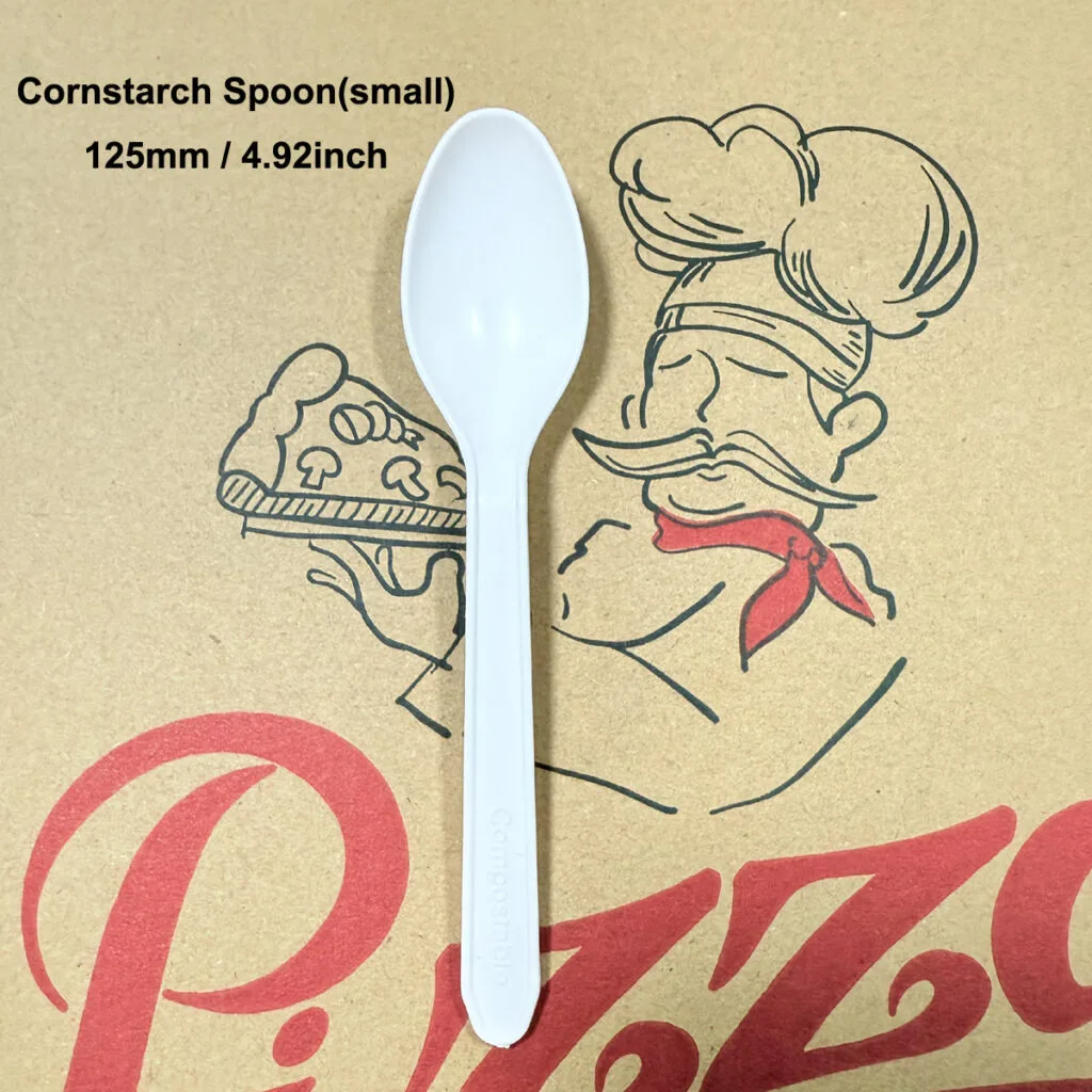 Kleiner 125mm Maisstärke biologisch abbaubarer Löffel auf Kraft-Pizzakarton-Hintergrund, umweltfreundliches kompostierbares Besteck für Desserts und Joghurt