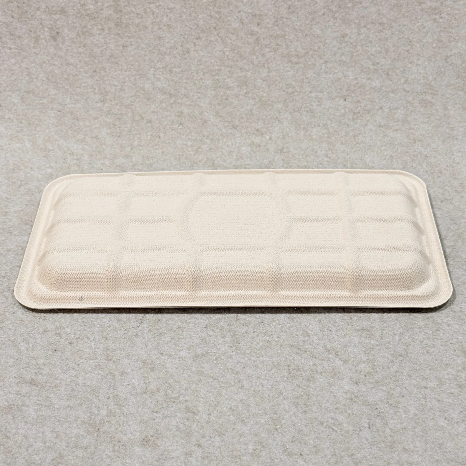 Pormenor do tabuleiro de embalagem de carne biodegradável mostrando a textura da pasta moldada e o acabamento dos bordos