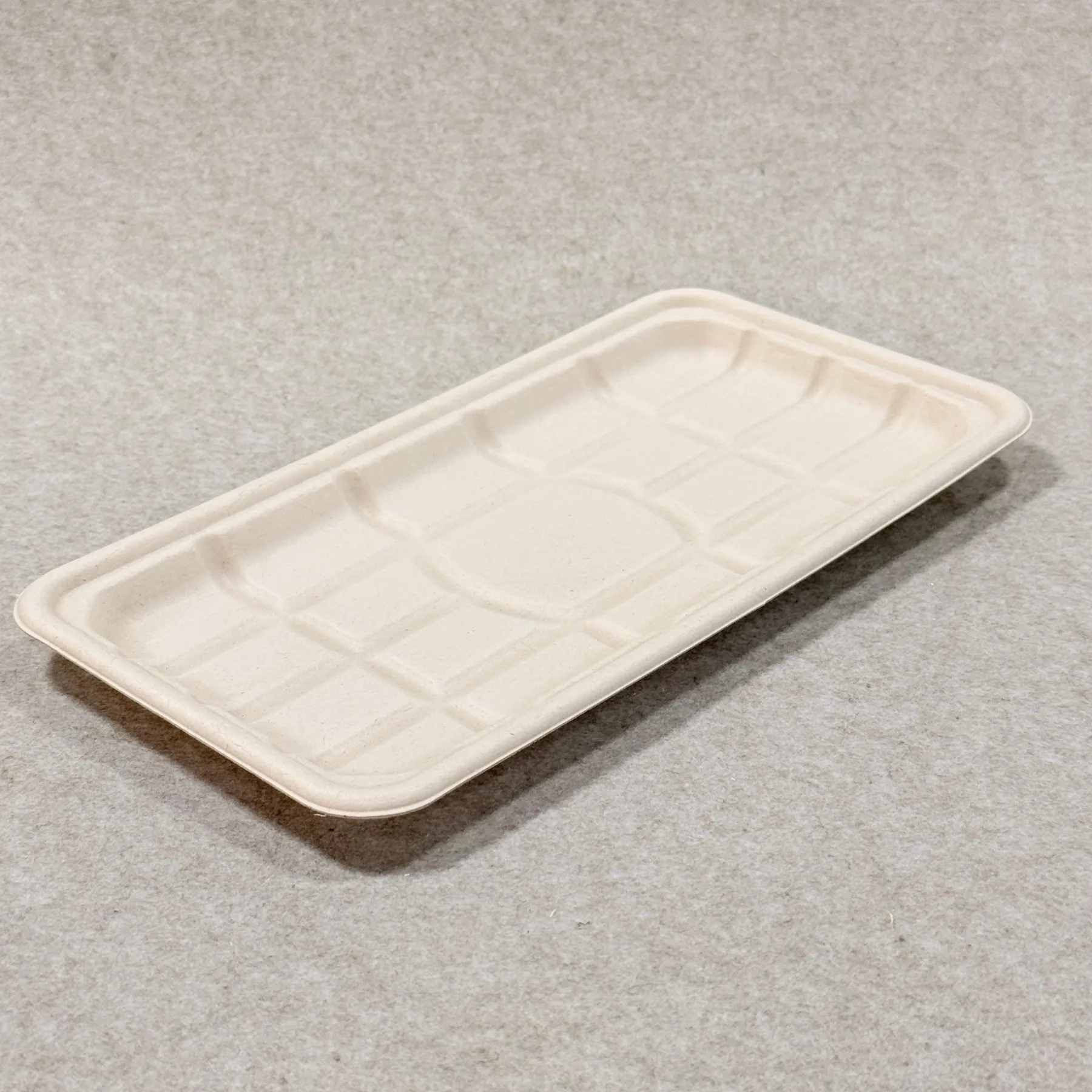 Pormenor do tabuleiro de embalagem de carne biodegradável mostrando a textura da pasta moldada e o acabamento dos bordos