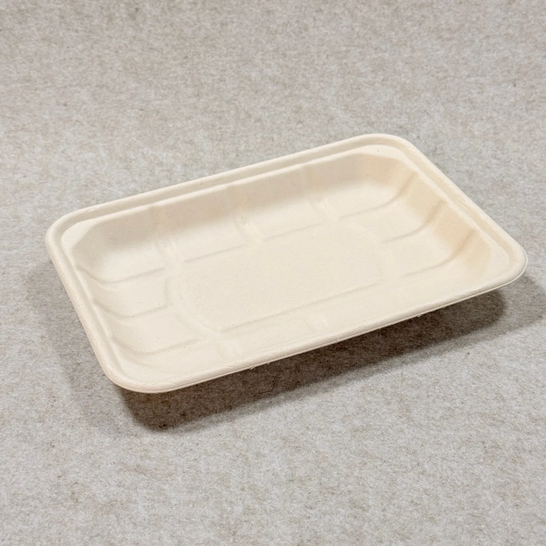 Dettaglio del vassoio di imballaggio compostabile per supermercati che mostra la struttura della pasta stampata e la finitura dei bordi