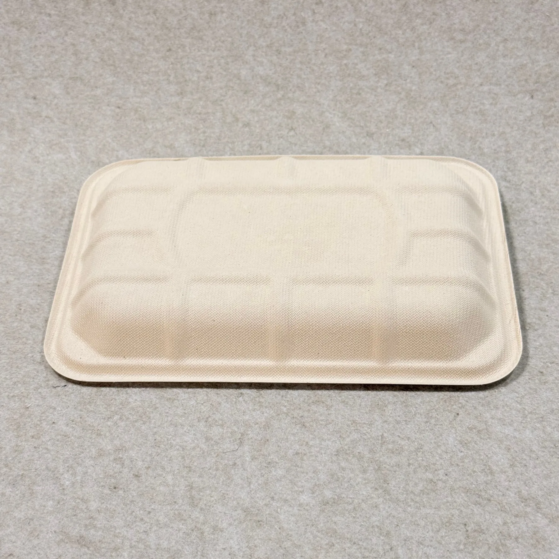 Dettaglio del vassoio di imballaggio compostabile per supermercati che mostra la struttura della pasta stampata e la finitura dei bordi