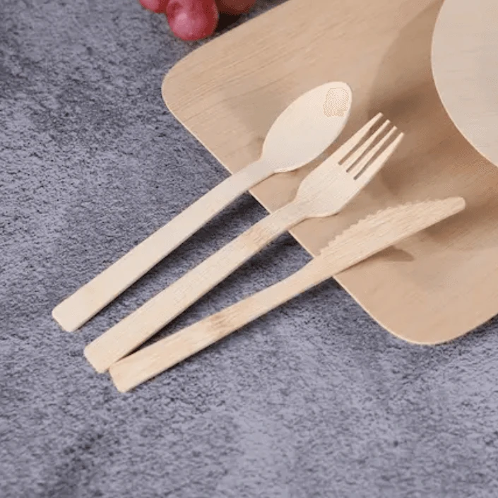 Light-colored knife, fork and spoon arranged beside a rectangular serving tray.